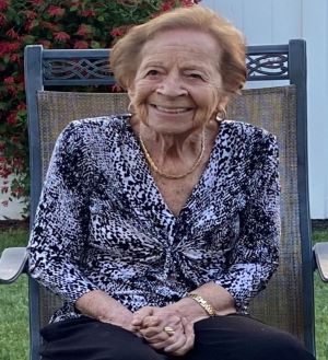 Joyce Kahane sitting in a metal chair outside.